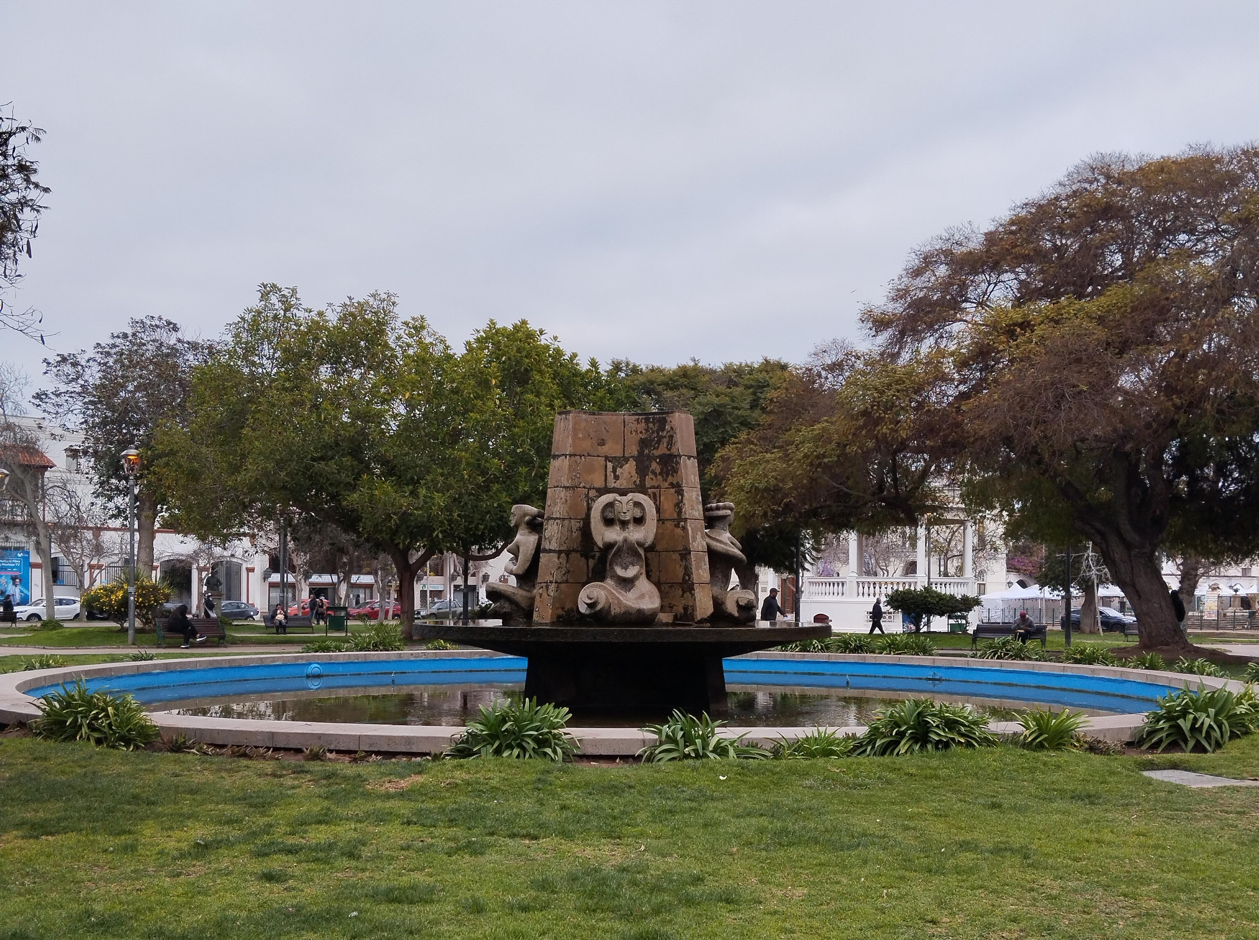 <img src="plaza-armas.jpg" alt="Fuente central con escultura en piedra rodeada de césped en la Plaza de Armas de La Serena">