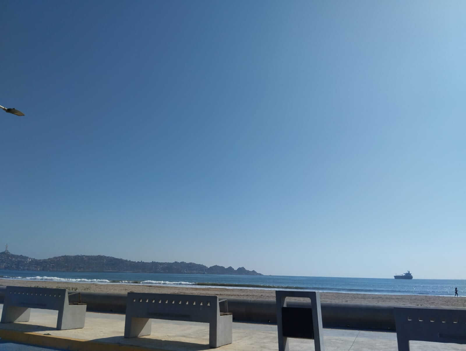 <img src="playa-vista.jpg" alt="Vista al mar desde el paseo costero de La Serena, con bancas de cemento y un barco en el horizonte">